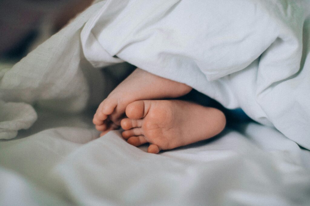 Close-up of tiny baby feet under a blanket, creating a cozy, cute vibe.